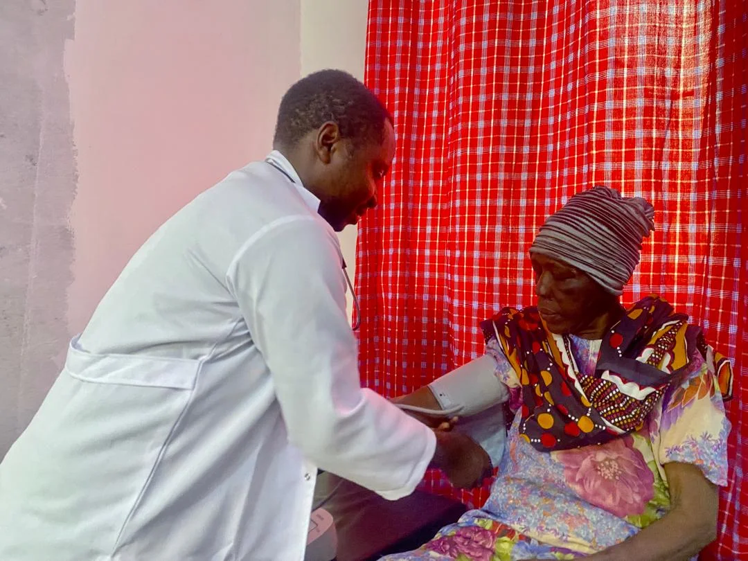 A clinician in a white coat taking an elderly woman's blood pressure