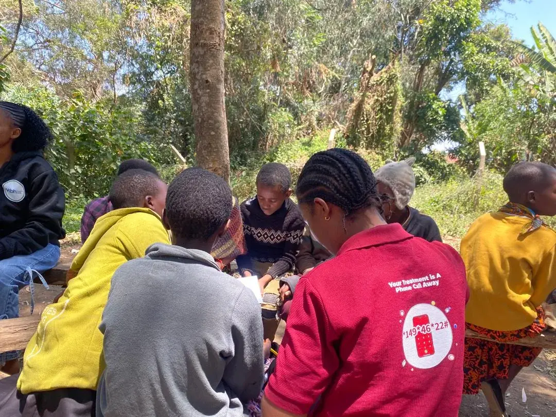 Health workers seated in a circle with members of the community
