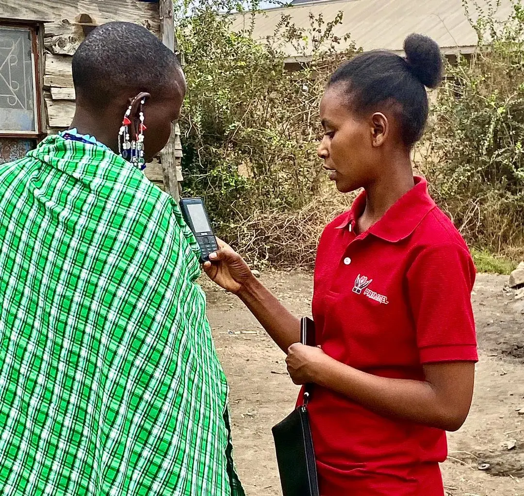A health worker in a red shirt speaking with a Maasai woman