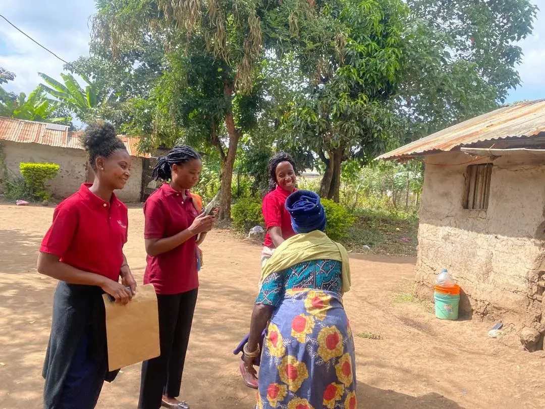 Health workers greeting a woman outside her home